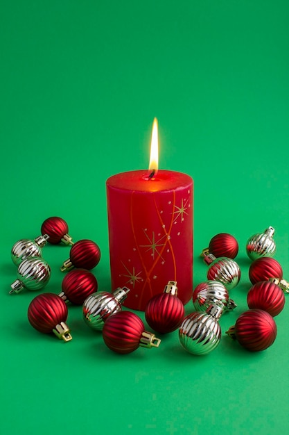 Composition de Noël avec une bougie allumée rouge et des haricots colorés sur le fond vert Espace de copie Emplacement vertical