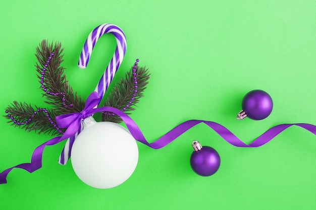 Composition de Noël avec boule blanche, branches d'épinette et canne au caramel sur la table verte. Copiez l'espace.