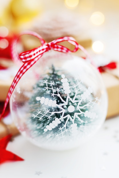 Composition de Noël avec boule décorative de flocon de neige, cadeaux et décorations pour sapin de Noël.