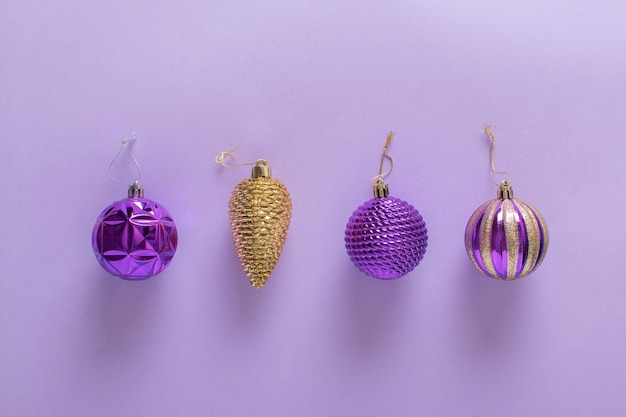Composition de Noël avec des boules de sapin de Noël violettes et un cône doré sur un violet clair