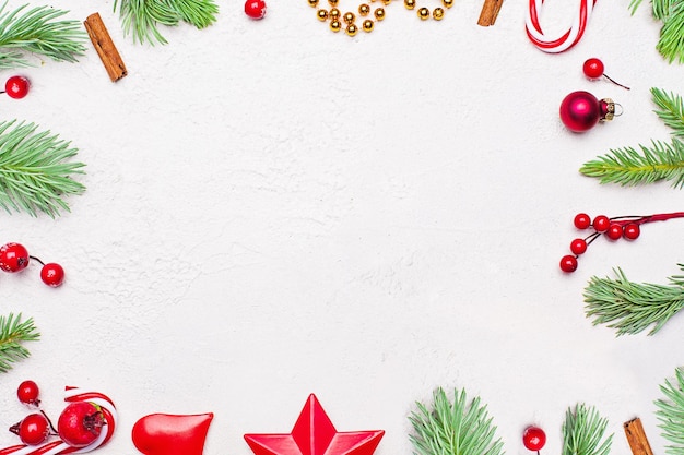 Composition de Noël avec branche de sapin de Noël vert baies de houx rouges et boules sur fond de texture de plâtre en stuc blanc Vue de dessus à plat avec espace de copie