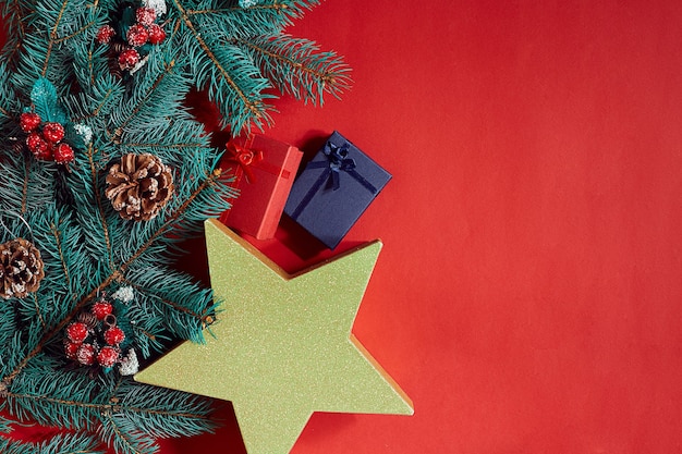 Composition de Noël de branches d'épinette de pommes de pin et pile de coffrets cadeaux sur fond rouge