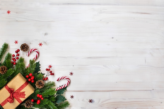 Composition de Noël avec des branches de sapin, des bonbons, des cadeaux, des pommes de pin et des étoiles sur du bois clair