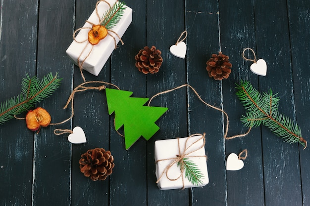 Composition de noël Cadeau de Noël, couverture tricotée, pommes de pin, branches de sapin sur bois.