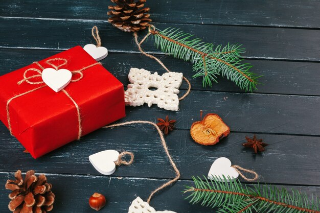 Composition de noël Cadeau de Noël, couverture tricotée, pommes de pin, branches de sapin sur bois.