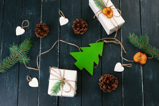 Composition de noël Cadeau de Noël, couverture tricotée, pommes de pin, branches de sapin sur fond en bois.