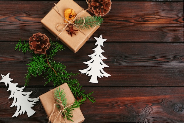 Composition de noël Cadeau de Noël, couverture tricotée, pommes de pin, branches de sapin sur fond en bois.