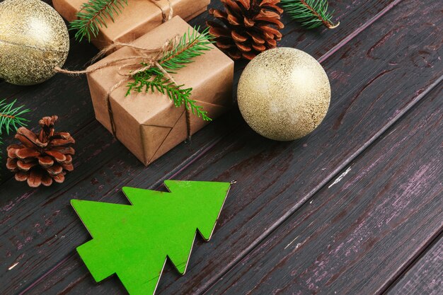 Composition de noël Cadeau de Noël, couverture tricotée, pommes de pin, branches de sapin sur fond en bois.