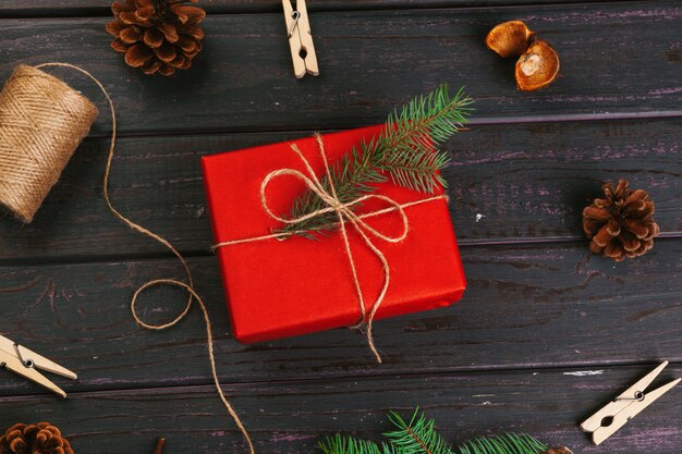 Composition de Noël. Cadeau de Noël, couverture tricotée, pommes de pin, branches de sapin sur table en bois.