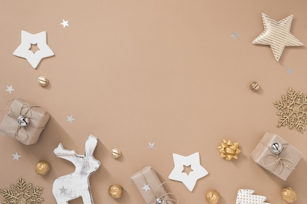 Composition de Noël. Cadre avec cadeaux, artisanat et décorations dorées sur fond beige pastel.