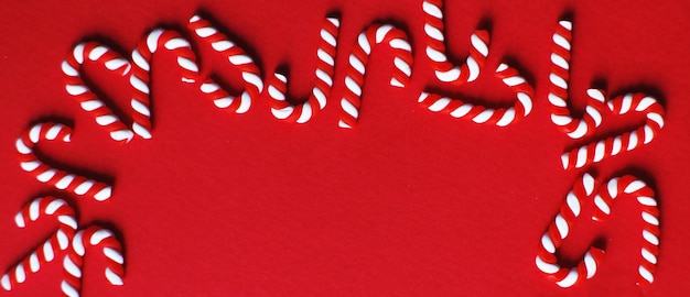 Composition de Noël avec cadre de cannes de bonbon sur fond rouge Copiez l'espace pour la bannière de texte