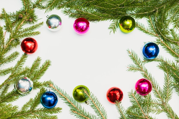 Composition de Noël avec cadre vide de boules colorées et de branches de sapin. ornement, décorations du nouvel an sur fond blanc. Modèle de carte de voeux maquette avec espace de copie, platement, vue de dessus.