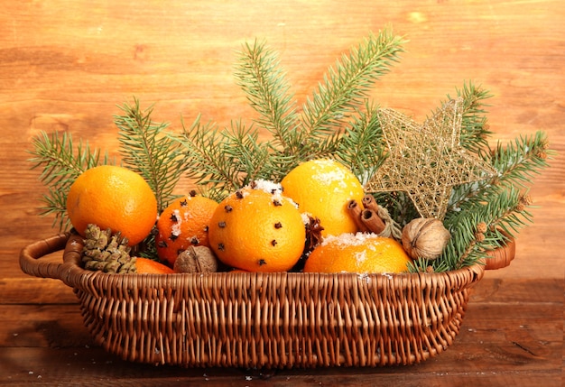 Composition de Noël dans le panier avec des oranges et sapin, sur fond de bois