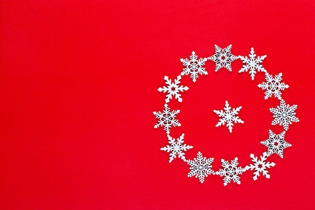 Composition de Noël. Décorations de guirlande de flocons de neige blanche sur fond rouge. Noël, hiver, concept de nouvel an. Mise à plat, vue de dessus, copie.