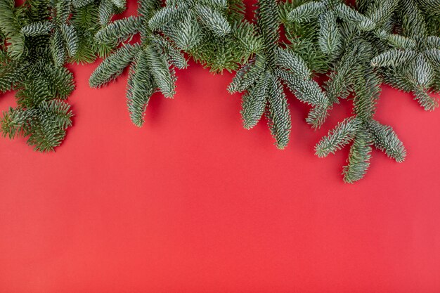 Composition de Noël. Décorations de Noël rouge, branches de sapin avec bosses sur fond rouge. Mise à plat, vue de dessus, espace copie