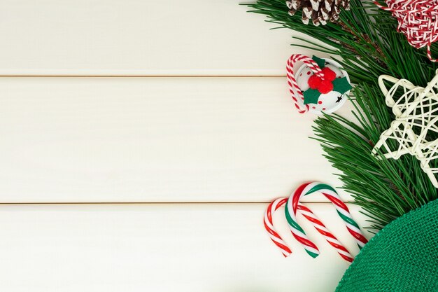 Composition de Noël ou du nouvel an sur fond en bois blanc. Branches de pin, clochette, canne à sucre