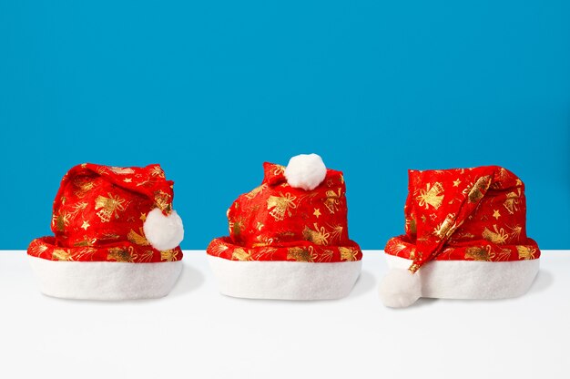 Composition de Noël faite de chapeaux de père Noël sur double fond bleu et blanc, vue de face, fond de Noël