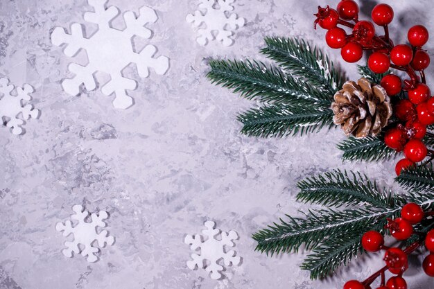 Composition de Noël ou d'hiver. Fond gris avec des flocons de neige blancs et des branches de sapin. Mise à plat, vue de dessus