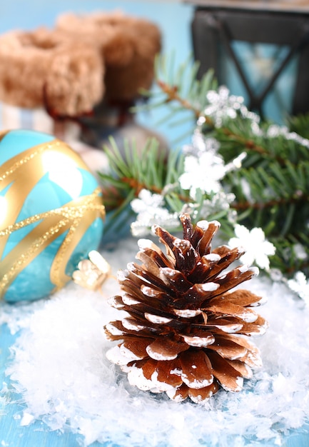 Composition de Noël lumineuse avec pomme de pin, boule bleue et bottes sur la neige