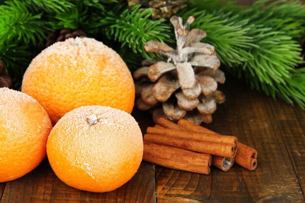 Composition de Noël avec des mandarines mûres givrées sur fond de bois