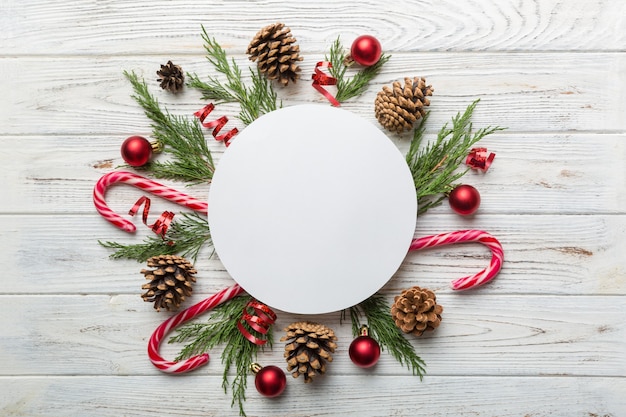 Composition de Noël à plat. Papier rond vierge, branches de pin, décorations de Noël sur fond coloré. Vue de dessus, copiez l'espace pour le texte