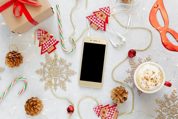 Composition de Noël à plat avec téléphone, tasse à café et décorations.