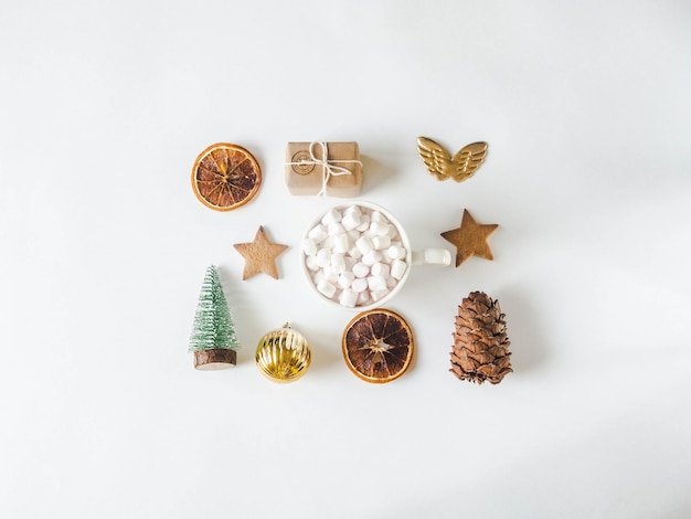 Composition de Noël plate - biscuit étoile, cadeau, tranches d'orange séchées, mug avec boisson chaude et guimauves, pomme de pin et sapin de Noël