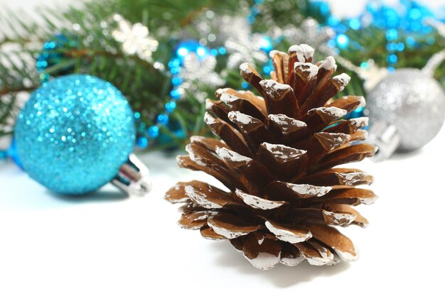 Composition de Noël avec une pomme de pin et une boule bleue sur blanc