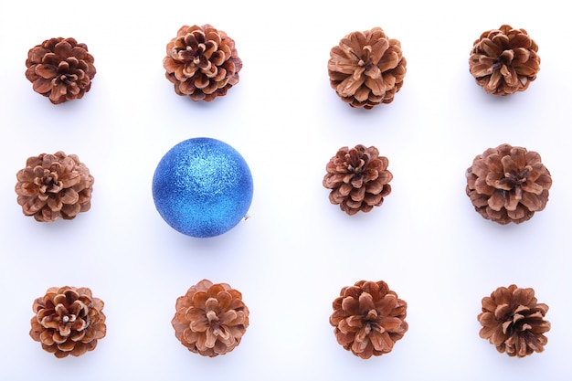 Composition de Noël avec des pommes de pin et une boule de Noël bleue sur fond blanc