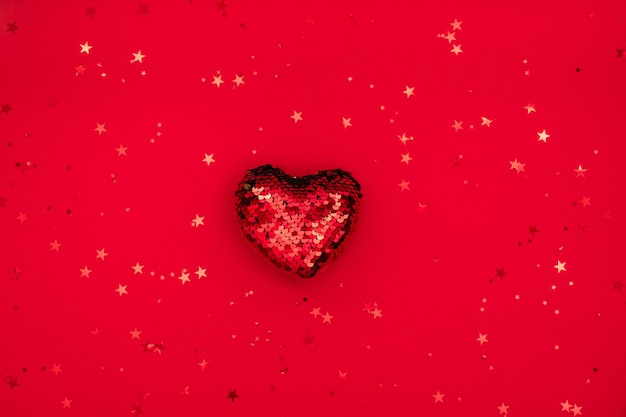 Composition de Noël ou de la Saint-Valentin faite de décoration de coeur scintillant et de paillettes sur une surface rouge. Joyeux Noël et bonne année, concept Happy Valentine. Mise à plat, vue de dessus