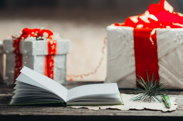 Composition de Noël sur une table en bois, une boîte de bloc-notes ouverte avec des cadeaux de stylo et une branche d'arbre de Noël