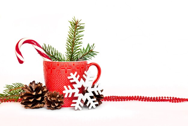 Composition de Noël avec tasse rouge, pommes de pin, aiguilles de sapin et flocon de neige