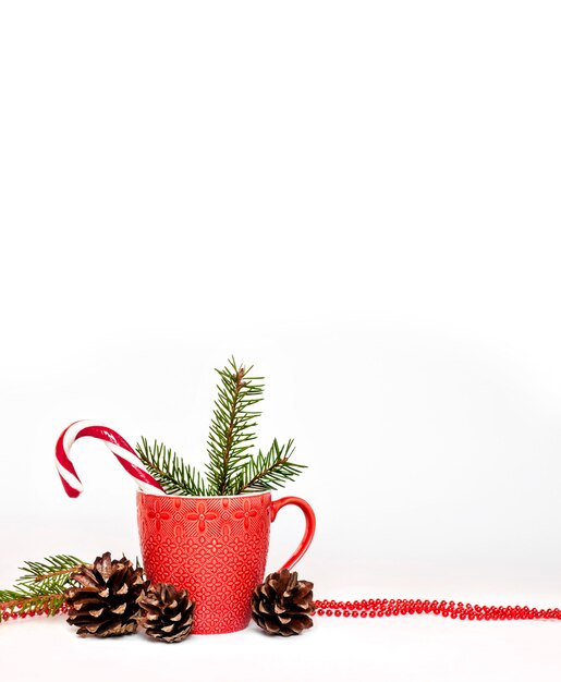 Composition de Noël avec tasse rouge, pommes de pin et aiguilles de sapin. Isolé sur une surface blanche. Copier l'espace