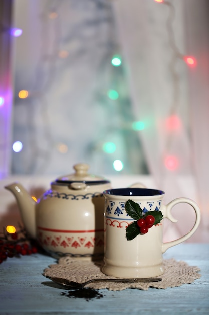 Composition de Noël avec tasse et théière de boisson chaude, sur table en bois