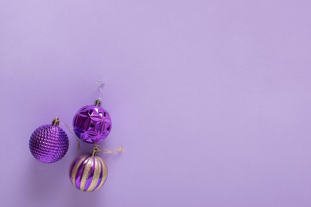 Composition de Noël avec trois boules de sapin de Noël violettes sur fond violet clair