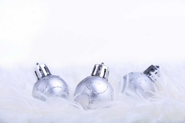 Composition de Noël ou de vacances avec des boules d'argent sur des plumes houleuses avec de la neige et des flocons de neige.