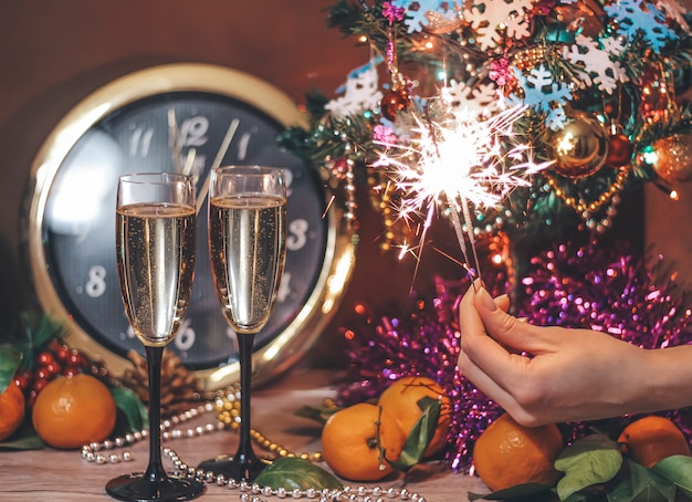 Photo composition de noël avec des verres de champagne et des feux de bengale dans la main de la femme