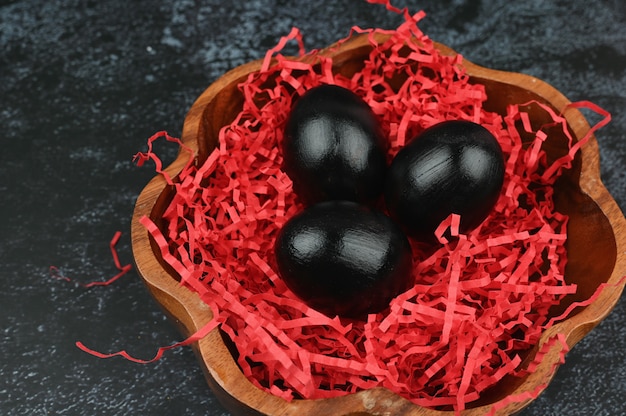 Composition avec des oeufs de Pâques noirs sur une surface colorée