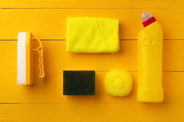 Composition d'outils de nettoyage à plat sur fond de bois jaune