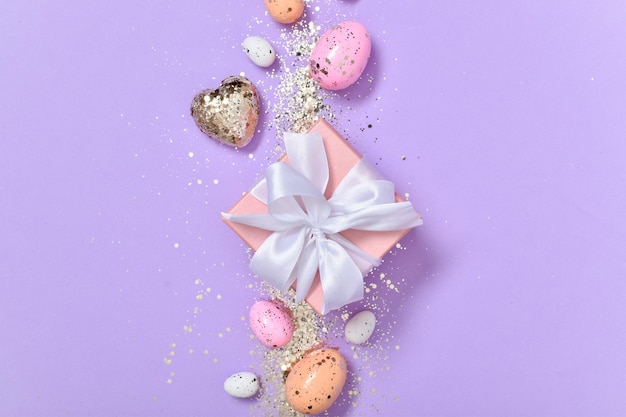 Composition de Pâques avec un cadeau et des oeufs de Pâques sur fond violet