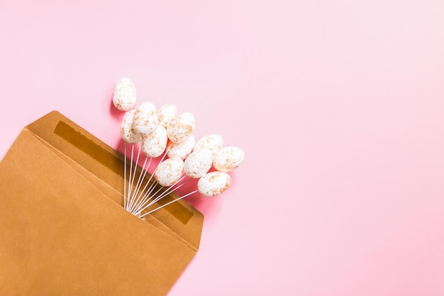 Composition de Pâques avec décor traditionnel. Petits œufs colorés décoratifs dans une enveloppe de papier kraft sur fond clair.