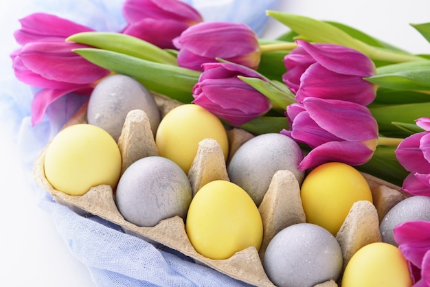 Composition de Pâques festive printemps gros plan d'oeufs pascaux et tulipes violettes sur fond blanc