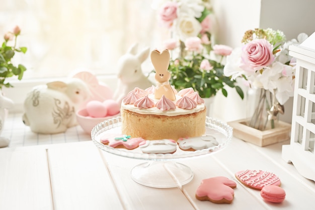 Composition de Pâques avec gâteau sucré avec glaçage aux fraises, lapins en céramique, œufs roses et roses