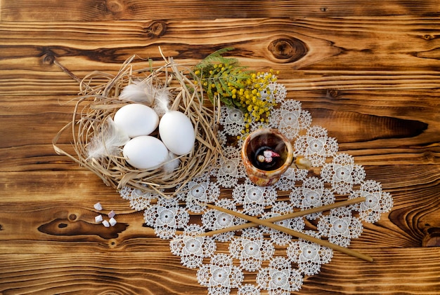 Composition de Pâques Oeufs bougies et branches d'un mimosa sur un gros plan de table