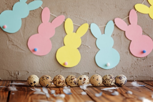 Composition de Pâques d'oeufs de caille de Pâques dans le panier et avec guirlande de lapin.