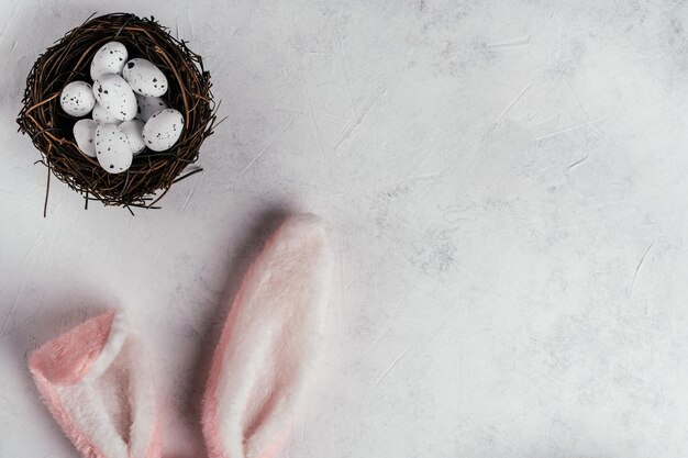 Composition de Pâques d'oeufs de caille à pois blancs dans un nid brun sur fond blanc et lapin rose jouet pelucheux cheveux oreilles