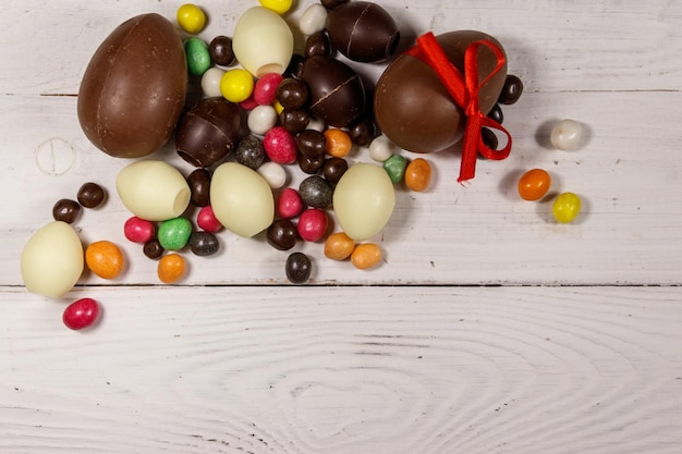 Composition de Pâques avec des oeufs en chocolat sur fond de bois blanc