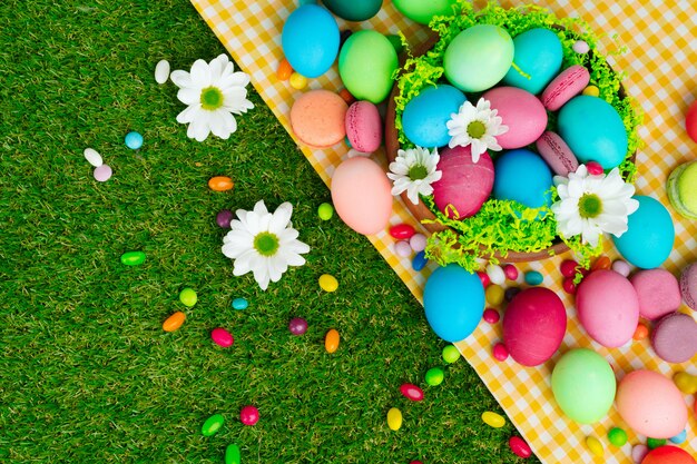 Composition de Pâques avec des oeufs colorés et des bonbons lumineux sur une nappe jaune