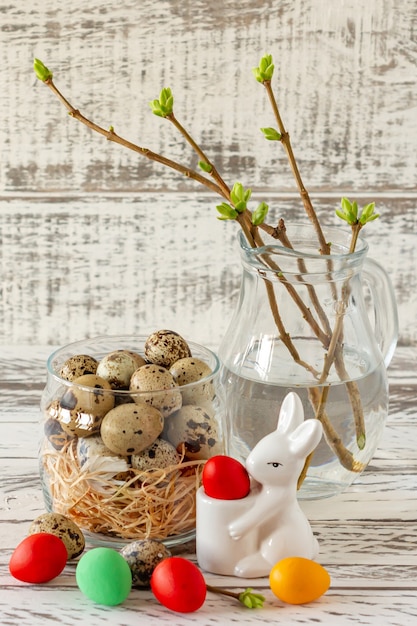 Composition de Pâques avec oeufs, lapin et brindilles de printemps dans un bocal en verre. Joyeuses Pâques.