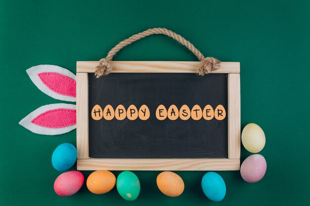 Composition de Pâques avec tableau noir, oeufs colorés et oreilles de lapin